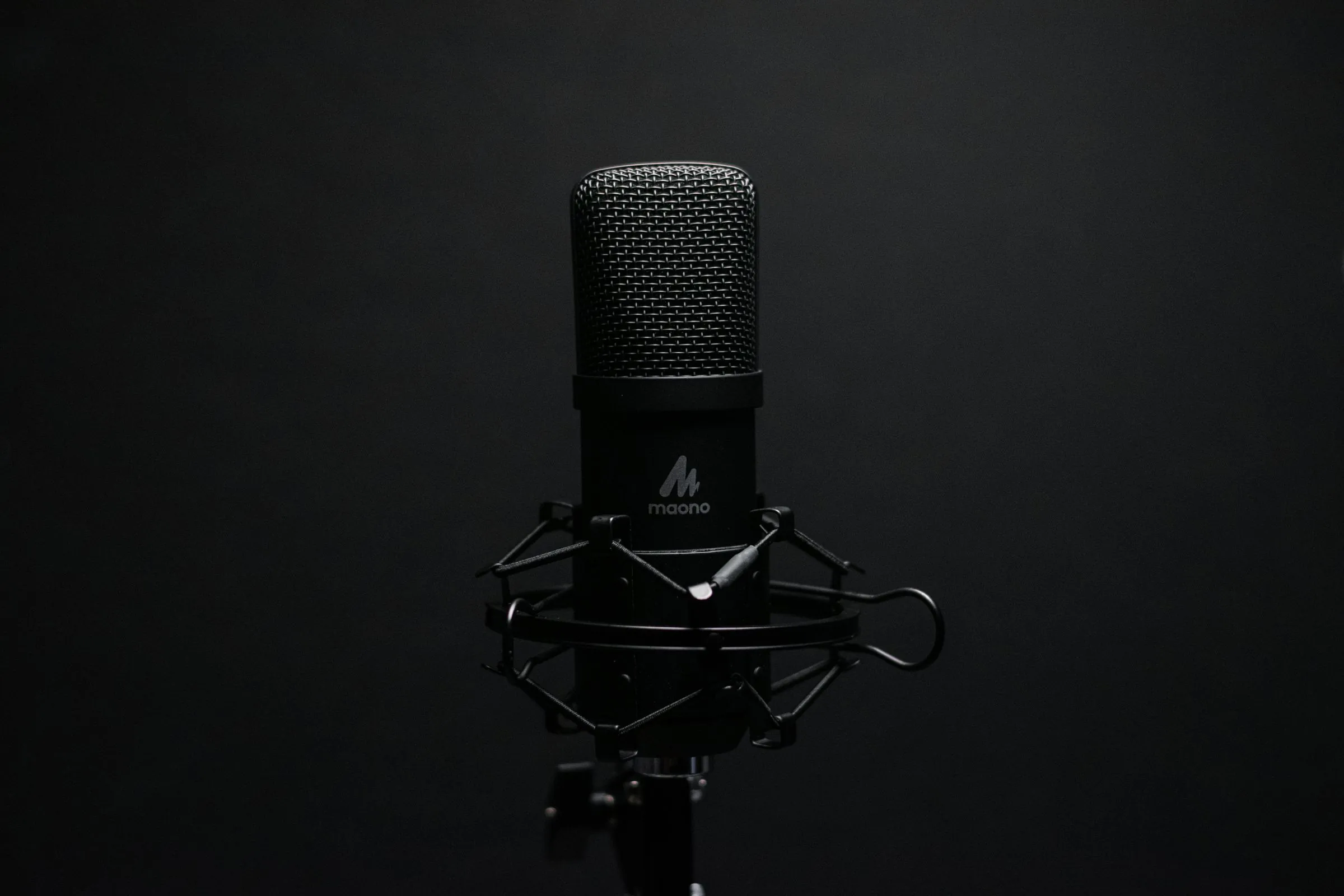Studio microphone with shock mount on a dark backdrop, perfect for audio recording setups.